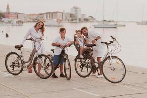 la familia feliz disfruta de una hermosa mañana junto al mar andando en bicicleta juntos y pasando tiempo juntos. el concepto de una familia feliz foto