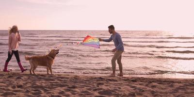 couple with dog having fun on beach on autmun day photo