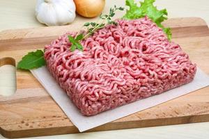 Minced meat on wooden board and wooden background photo