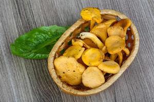 Chanterelle in a basket on wooden background photo