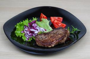 bistec en el plato y fondo de madera foto