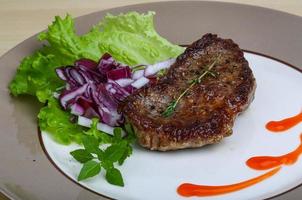 bistec en el plato y fondo de madera foto