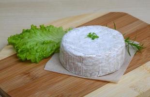 queso camembert sobre tabla de madera y fondo de madera foto