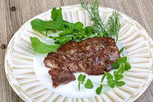 Roasted beef on the plate and wooden background photo