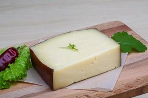 Hard cheese on wooden board and wooden background photo