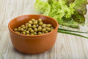 Marinated peas in a bowl on wooden background photo