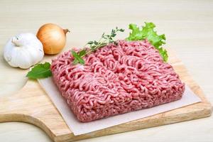 Minced meat on wooden board and wooden background photo