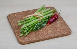 Raw asparagus on wooden board and wooden background photo