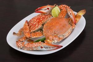 Boiled crabs on the plate and wooden background photo