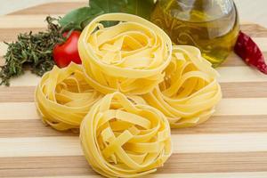 Raw fettuccine on wooden background photo