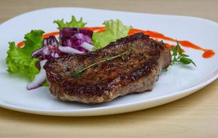 Beefsteak on the plate and wooden background photo