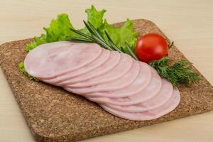 Sliced ham on wooden board and wooden background photo