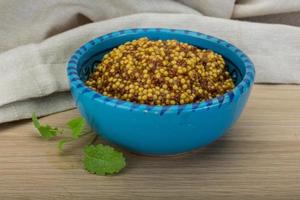 French mustard in a bowl on wooden background photo
