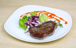 bistec en el plato y fondo de madera foto