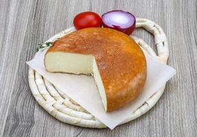 Suluguni cheese on wooden board and wooden background photo
