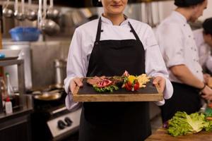 female Chef holding beef steak plate photo