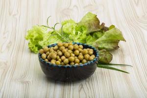 Marinated peas in a bowl on wooden background photo