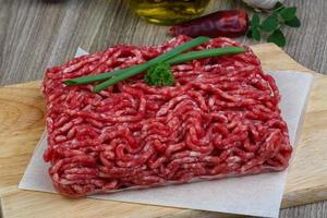 Minced beef on wooden board and wooden background photo