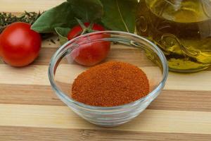 Paprika powder in a bowl on wooden background photo