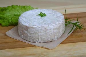 queso brie sobre tablero de madera y fondo de madera foto