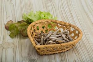 Dries anchovy in a basket on wooden background photo