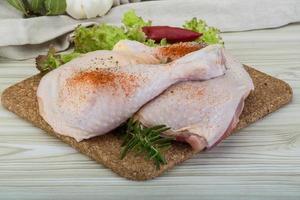 Chicken thigh on wooden board and wooden background photo