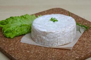 queso camembert sobre tabla de madera y fondo de madera foto