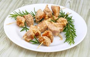 Chicken skewers on the plate and wooden background photo