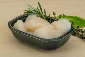 Raw scallops in a bowl on wooden background photo