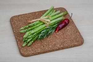 Raw asparagus on wooden board and wooden background photo