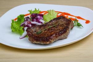 Beefsteak on the plate and wooden background photo