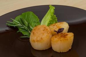 Grilled scallops on the plate and wooden background photo