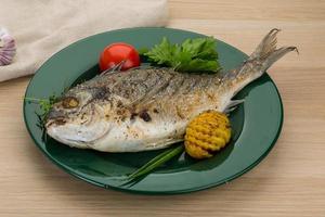 Grilled dorado on the plate and wooden background photo