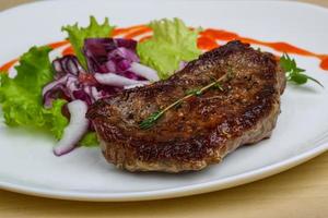 Beefsteak on the plate and wooden background photo