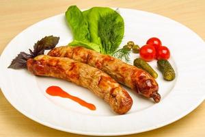 Grilled sausages on the plate and wooden background photo