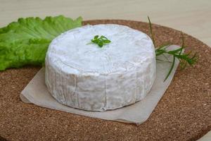 Brie cheese on wooden board and wooden background photo