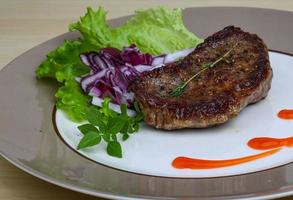 Beefsteak on the plate and wooden background photo