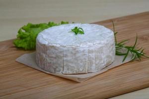 queso camembert sobre tabla de madera y fondo de madera foto