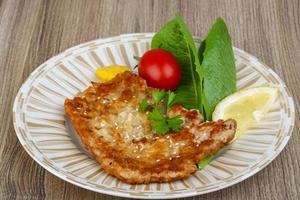 Pork schnitzel on the plate and wooden background photo