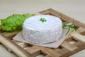 queso camembert sobre tabla de madera y fondo de madera foto