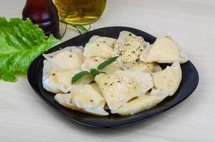 Vareniki on the plate and wooden background photo