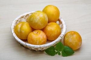 Yellow plums in a basket on wooden background photo