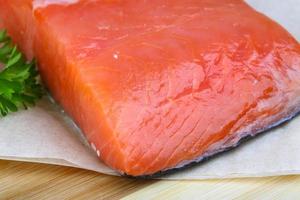 Salmon fillet on wooden board and wooden background photo