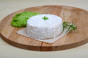 Brie cheese on wooden board and wooden background photo