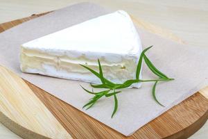 queso brie sobre tablero de madera y fondo de madera foto