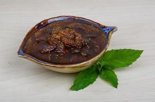 Mulberry jam in a bowl on wooden background photo