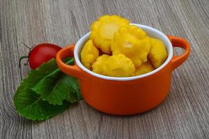 Pickled patissons in a bowl on wooden background photo