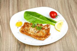 Pork schnitzel on the plate and wooden background photo