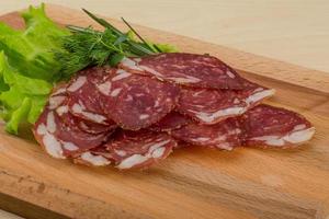 Sliced salami on wooden board and wooden background photo