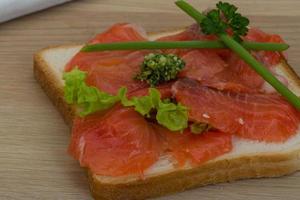 Salmon sandwich on wooden background photo